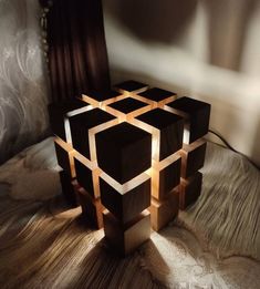 a lamp made out of wooden blocks on a bed with a curtain in the background