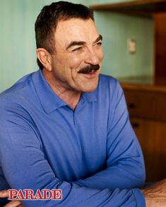 a man with a moustache on his face sitting in front of a desk