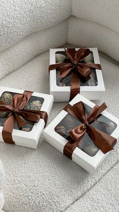 three white boxes with brown ribbons and pictures in them