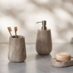 two toothbrushes and a soap dispenser sitting on a marble counter