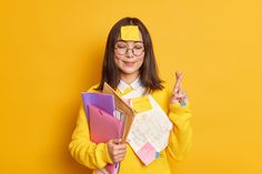 a woman in yellow sweater holding folders and pointing to the side with index finger