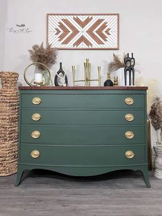 a green dresser with gold knobs and decorative items on it's top shelf