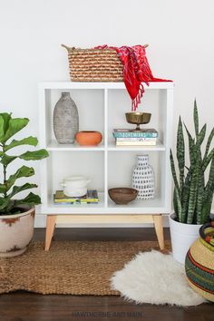 a white bookcase with plants and other items on the shelves in front of it