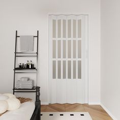 a room with a white door and some shelves on the wall next to a bed