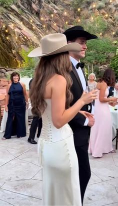 a man and woman dressed in formal wear standing next to each other at a party