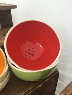 two bowls sitting next to each other on top of a wooden table and one has a watermelon in it