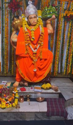 a statue of the hindu god maha in front of flowers and garlands