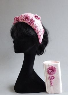 a black mannequin head with a pink flowered hat on it's head