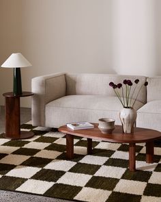 a living room with a checkered rug, coffee table and vase on the floor