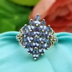 GLAMOROUS Sterling Silver Iolite Cluster Diamond Filigree Ring Made in the 1980s. This Over-the-Top, Statement Ring features Natural Iolite Gemstones that are a Beautiful Periwinkle Color and are Cluster Set. There are Two Small Natural Diamond Accents on Either Side with Ornate Filigree Detail that Gives this Piece a Vintage Flare. The Iolites measure 2mm each The Ring Itself measures 7/8'' in Length x 13/16'' Wide Split Shank Filigree Design Size US 8.75 Weighs 5.49 Grams Simple Stone Ring, Iolite Jewelry, Periwinkle Color, Vintage Cocktail Ring, Roanoke Va, Semi Precious Jewelry, Vintage Flare, Sterling Silver Engagement Rings, Diamond Cocktail Rings