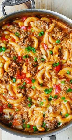 a skillet filled with pasta and meat in tomato sauce, topped with green onions