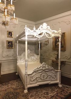 a white bed sitting on top of a rug next to a chandelier in a bedroom