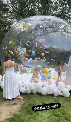 a woman standing in front of a giant bubble filled with confetti