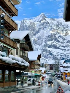 the mountains are covered in snow as people walk down the street