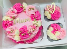 two cupcakes with pink and white frosting in a box, one has a name on it