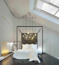 a white bed sitting under a window next to a wooden floor with lights on it