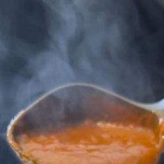 a spoon full of soup is being held by someone's hand with steam coming out of it