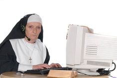 a nun sitting at a desk with a computer and mouse in front of her,