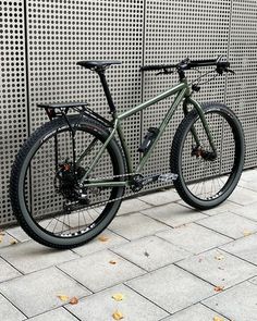 a green bike parked next to a wall with perforated metal panels on it