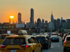 the sun is setting on a busy city street with many cars and trucks in traffic