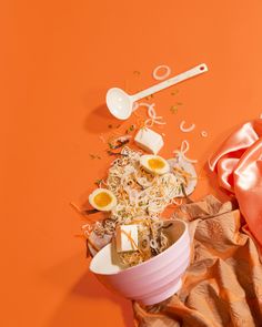 an orange background with food and utensils on it, such as eggs in a bowl