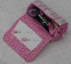 a pink and white purse with some items in it's pouch on a polka dot tablecloth