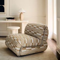 a living room with a checkered chair and table next to it on top of a hard wood floor