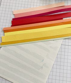 several pieces of paper laid out on top of a cutting mat with crayons