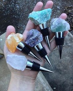 a person holding five different colored rocks in their palm with metal tips and spikes on them