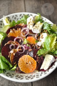 a salad with oranges, lettuce and feta cheese in it on a white plate