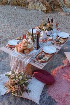 a table set up on the beach with food and drinks for two people to eat