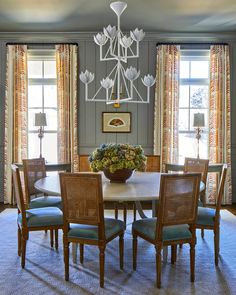 a dining room table with chairs and a chandelier hanging from it's ceiling