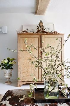 a vase filled with flowers sitting on top of a wooden table next to a cabinet