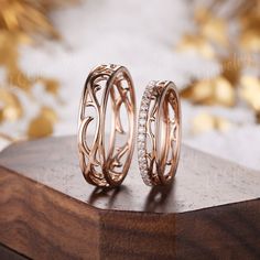 two gold rings with diamonds on top of a wooden table