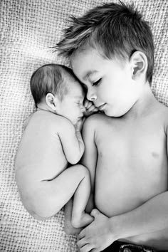 black and white photograph of two babies cuddling on top of each other, sleeping