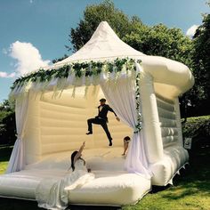 an inflatable wedding tent with two people jumping on the bed and one woman laying down