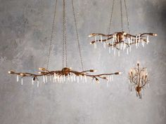 two chandeliers hanging from chains in a room with concrete walls and flooring