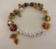 a bracelet that says willow with autumn leaves and beads on the front, along with an acrylic leaf charm