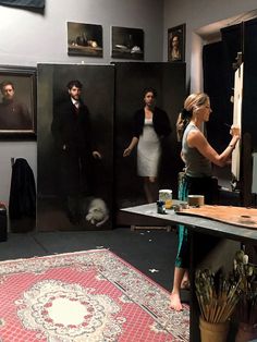 a group of people standing around in front of pictures on the wall and rugs