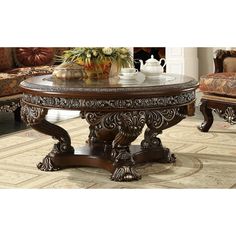 an ornately carved coffee table in a living room with chairs and couches behind it