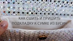 a woman's hand holding onto a white dress with lots of crystal beads on it