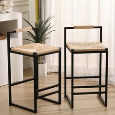 two black barstools sitting next to each other in front of a potted plant