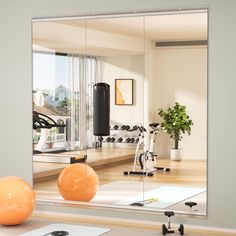 an exercise room is reflected in the mirror on the wall next to yoga mat and exercise balls