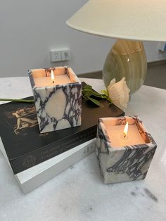 three marbled candles sitting on top of a table next to a book and lamp