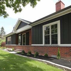 a house with black siding and white trim on the windows is shown in this image