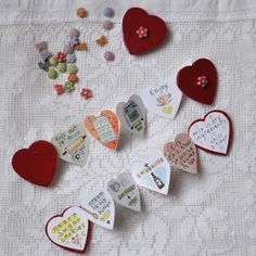 several hearts are arranged on a white tablecloth with words and pictures pinned to them