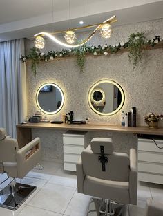 a hair salon with two mirrors on the wall and lights hanging from the ceiling above it