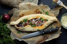 an open pita bread with meat and cheese on it next to some parsley