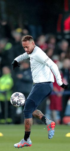 a man kicking a soccer ball on top of a field