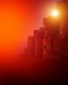 the light shines brightly in the foggy sky above some brick buildings on a hill